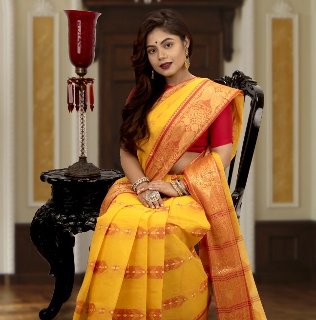 Woman clad in saree sitting on a chair