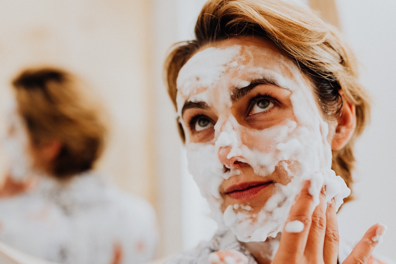 Woman applying face wash on her face