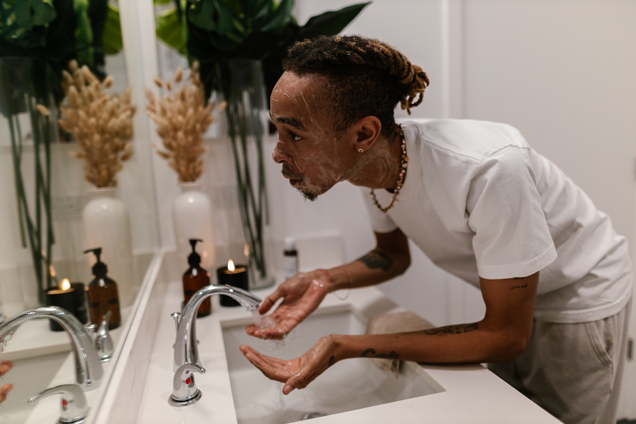 Young man washing his face with face wash 