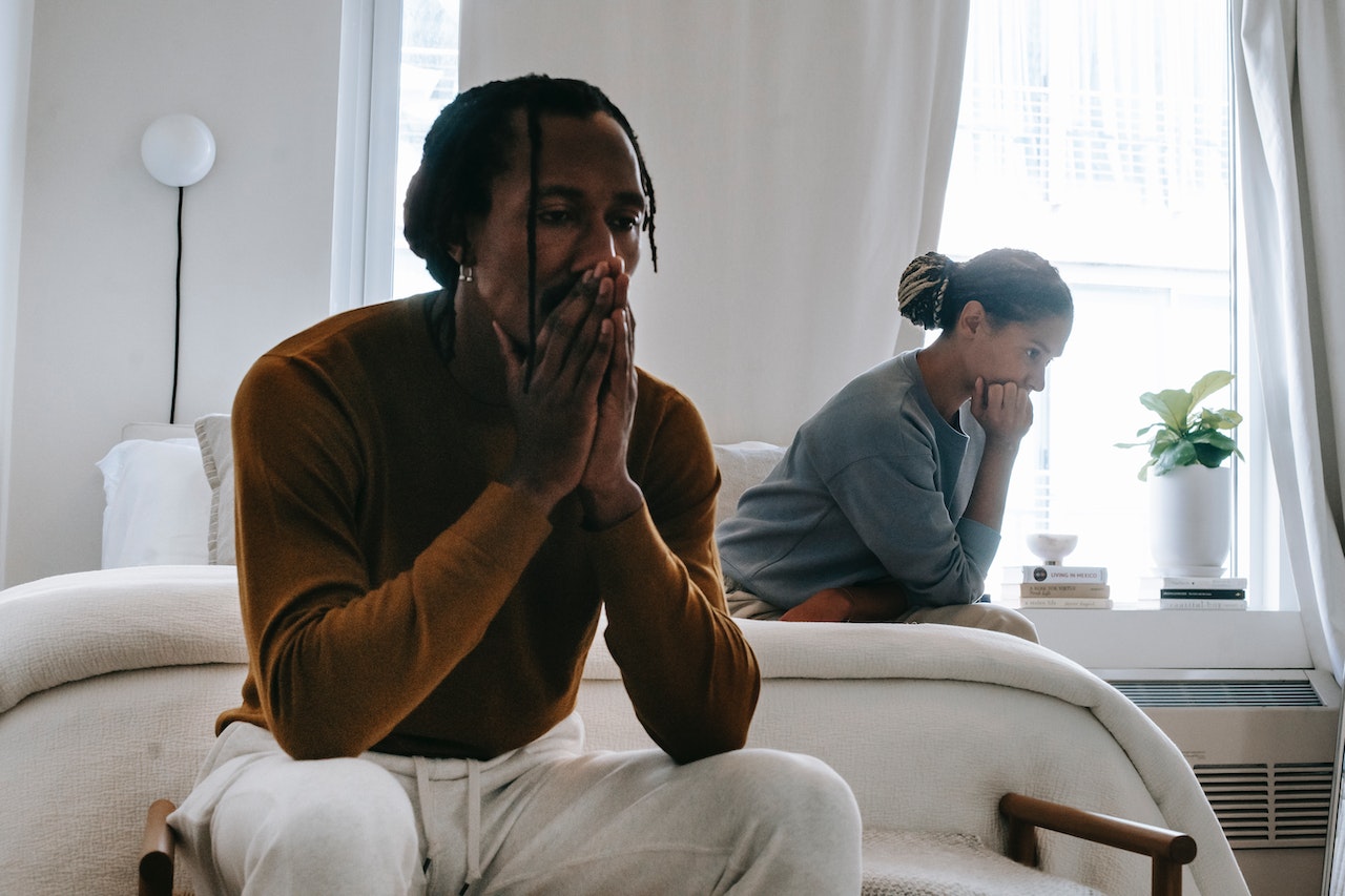 Unhappy black couple sitting on bed after having argument