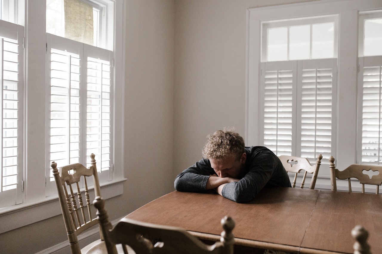 Worried Man sitting on wooden chair with head down