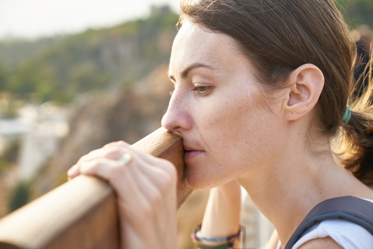 woman overthinking while standing in front of wooden plank