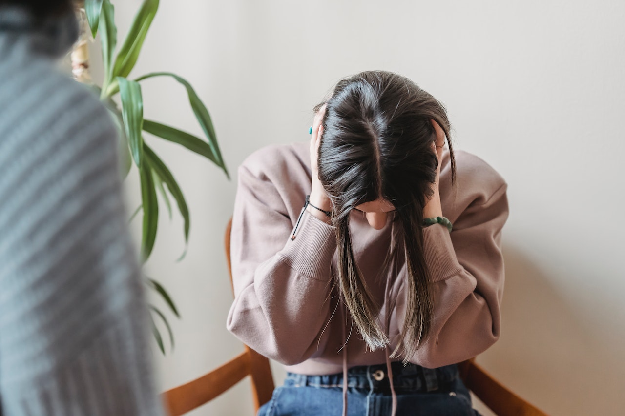 Woman with head down and ears covered bearing shouting of other woman