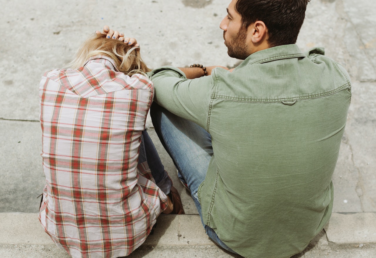 man and woman sitting on sidewalk discussing relationship issue