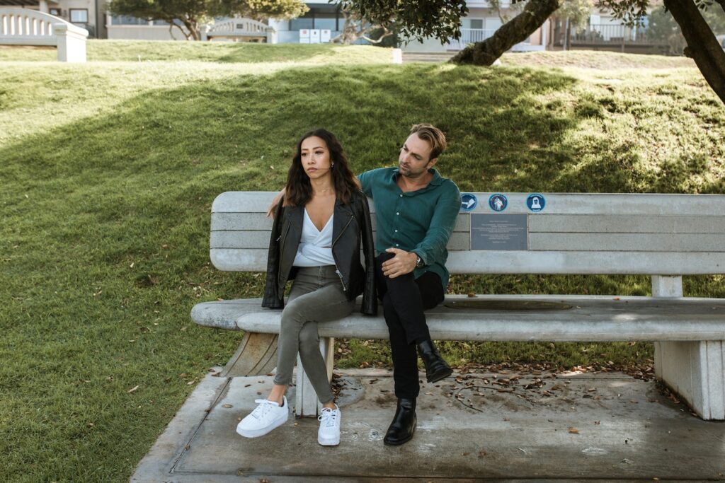 Man And Woman Sitting On A Bench Having A Discussion