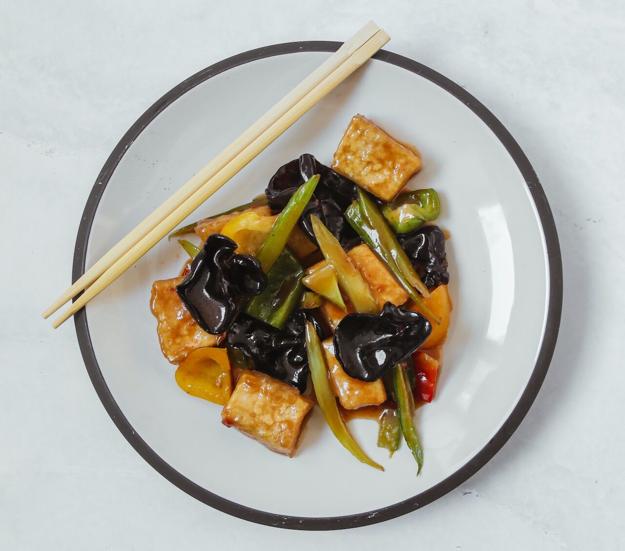 Stir Fried Vegetables, tofu and Chopsticks on a Ceramic Plate
